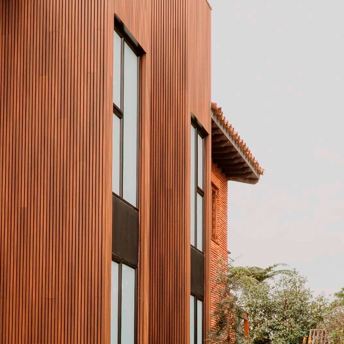 Revestimiento de fachada con cladding Wallpanel WPC color madera instalado en muro exterior, terminación tipo madera en aplicación vertical