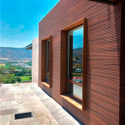 Fachada moderna revestida con cladding Wallpanel WPC color madera en exterior, solución de revestimiento para muro y envolvente arquitectónica