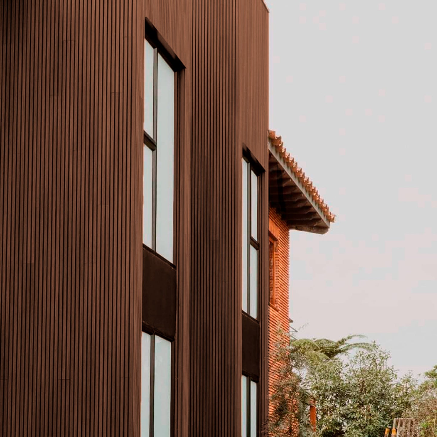 Revestimiento de fachada con cladding Wallpanel WPC color chocolate instalado en muro exterior, terminación tipo madera en aplicación vertical