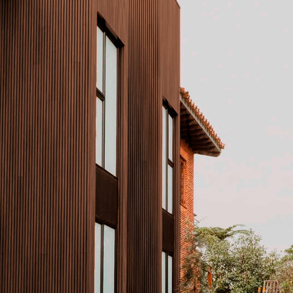 Revestimiento de fachada con cladding Wallpanel WPC color chocolate instalado en muro exterior, terminación tipo madera en aplicación vertical