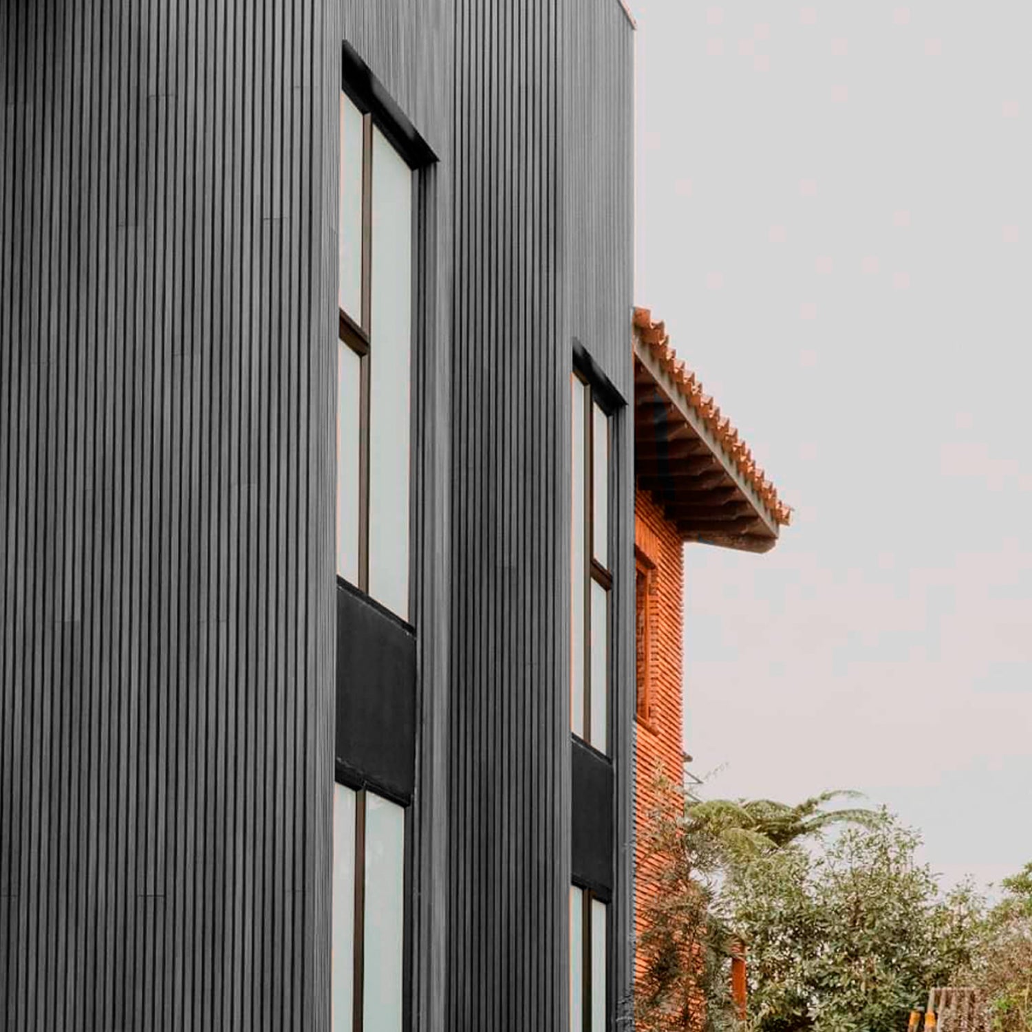 Revestimiento de fachada con cladding Wallpanel WPC gris instalado en muro exterior, terminación tipo madera en aplicación vertical